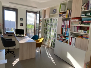 Réalisation de l'agencement bureaux professions libérales par In'Pulsion, pour un cabinet d'orthophonie. Bureau, fauteuils et étagères